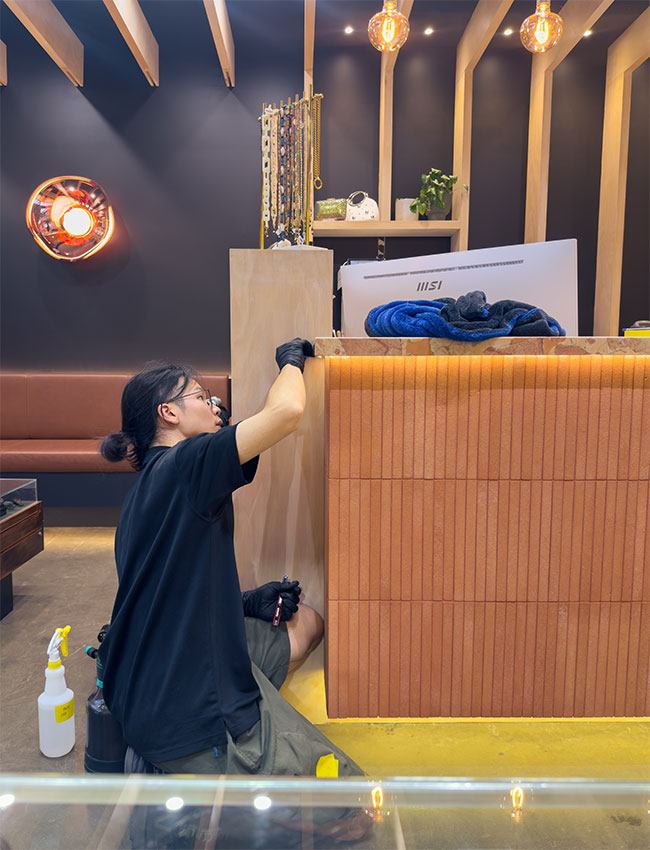 Masori installer working on site, applying protection to the base of a retail counter.